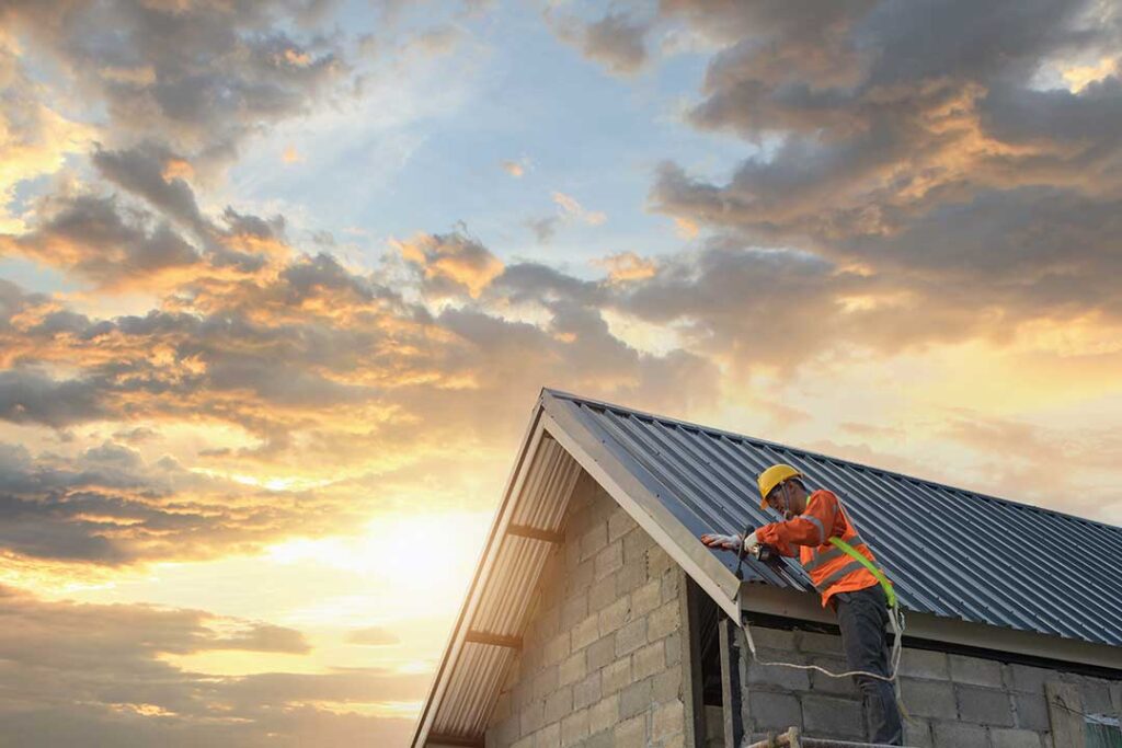 Rainwater flows from roof shingles into clean gutters and downspouts beside a residential home.