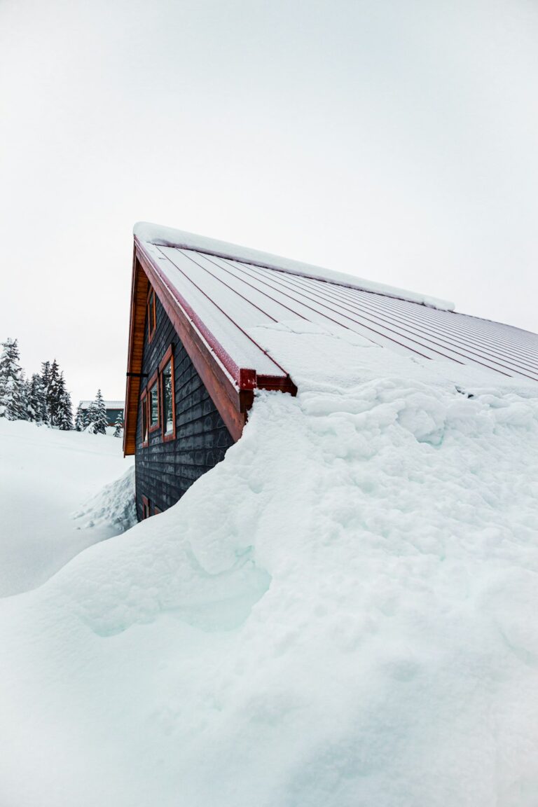 A homeowner measures roof rise from an attic using a level and tape measure beside visible rafters.